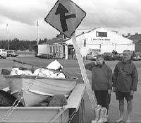 Mary and Des Gill beside the dingy of rubbish and the road sign that they found in the inlet